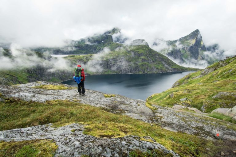 hiker-standing-beside-lake-lofoten-mountains-foggy-day.jpg